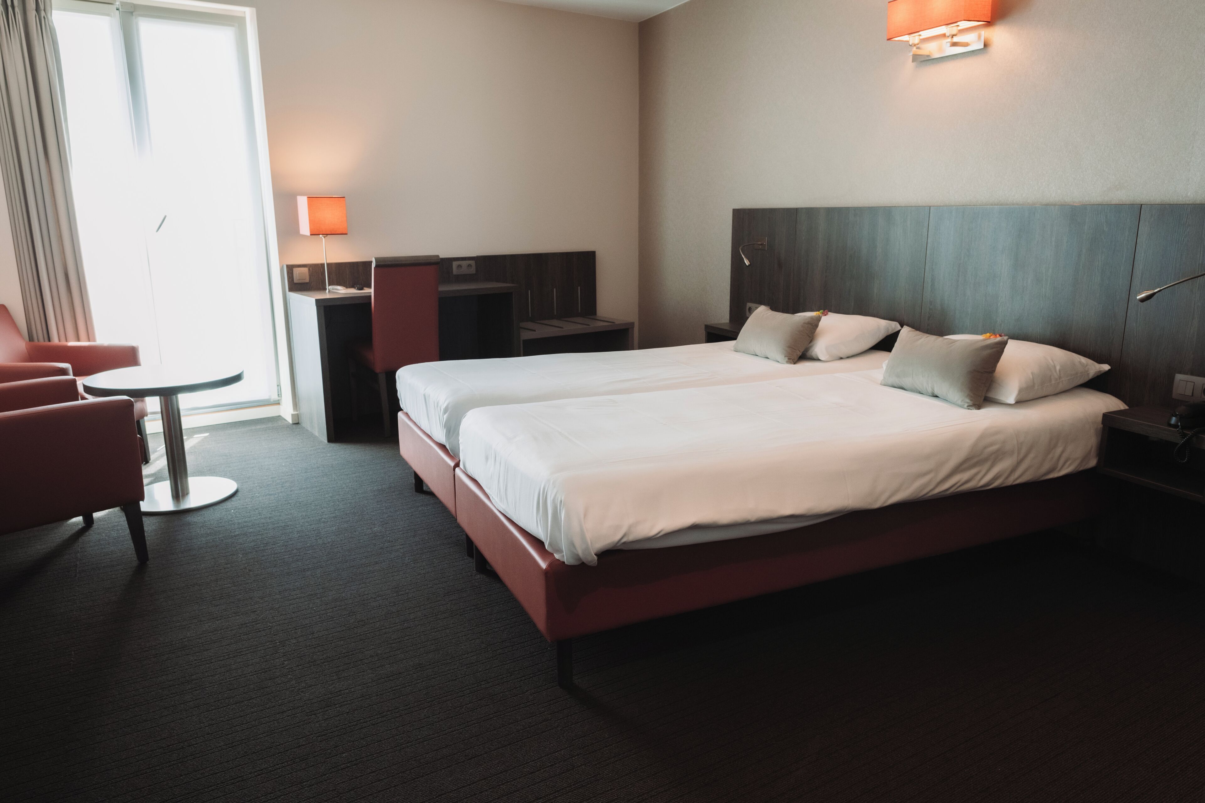 Ein Hotelzimmer mit einem großen Bett, einem Schreibtisch, einem Stuhl und einer Lampe.