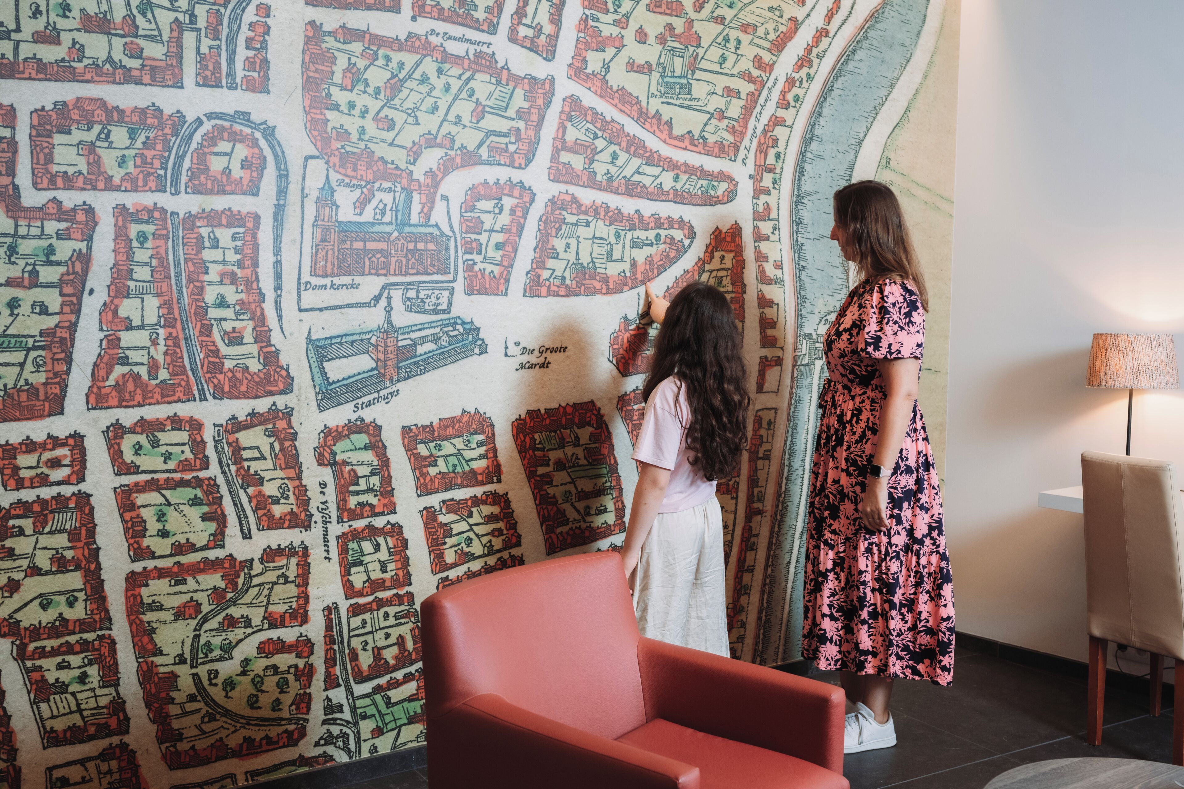 Una habitación con un gran mapa mural, una silla roja y una lámpara.