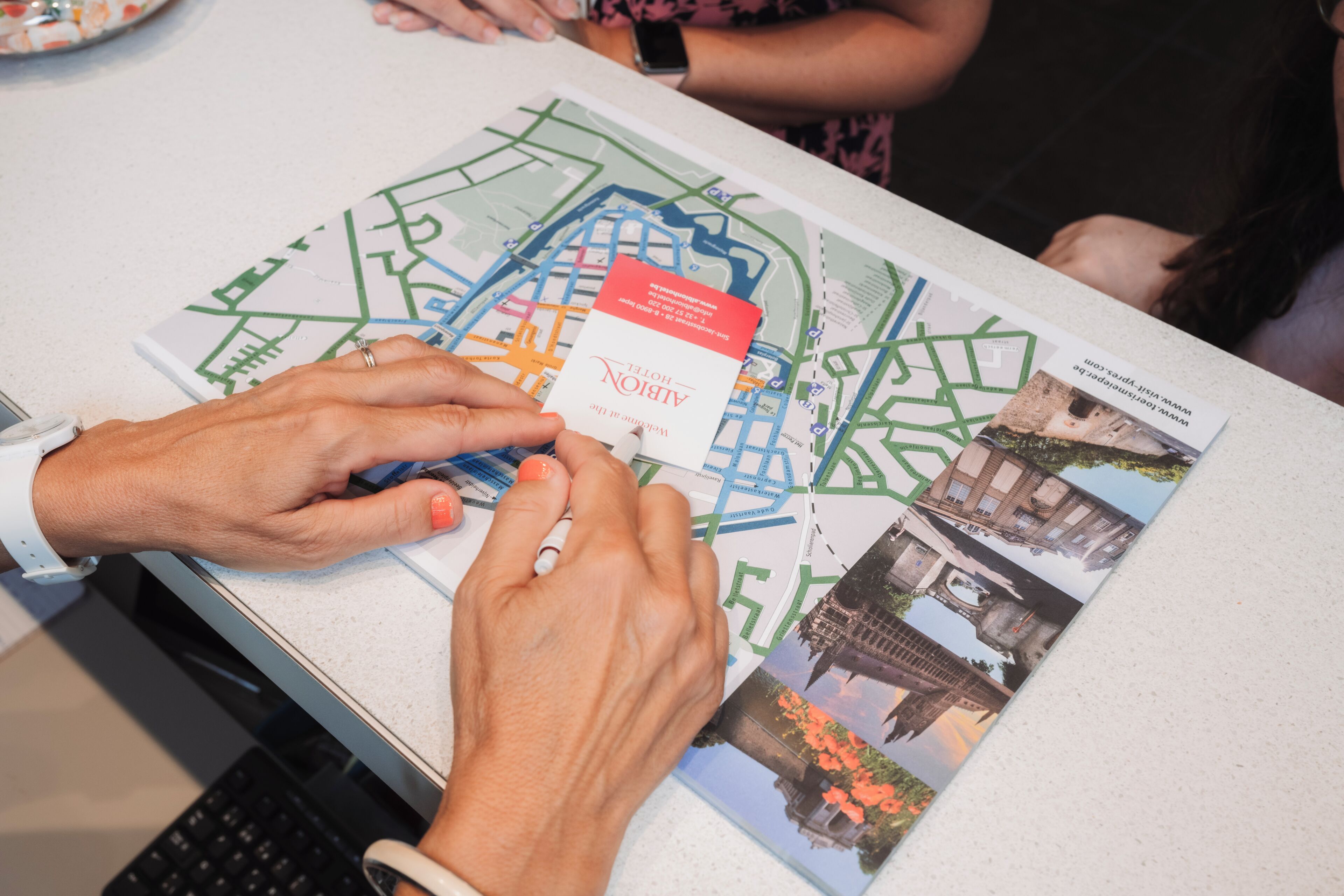 A person examining a map with a red card on top, surrounded by printed images of buildings.