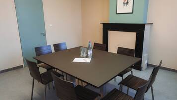 A conference room with a rectangular table, six chairs, a water bottle, a glass, and a framed picture on the wall.