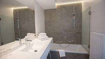 Un baño moderno con un lavamanos grande de color blanco, una mampara de ducha de cristal y una bañera.