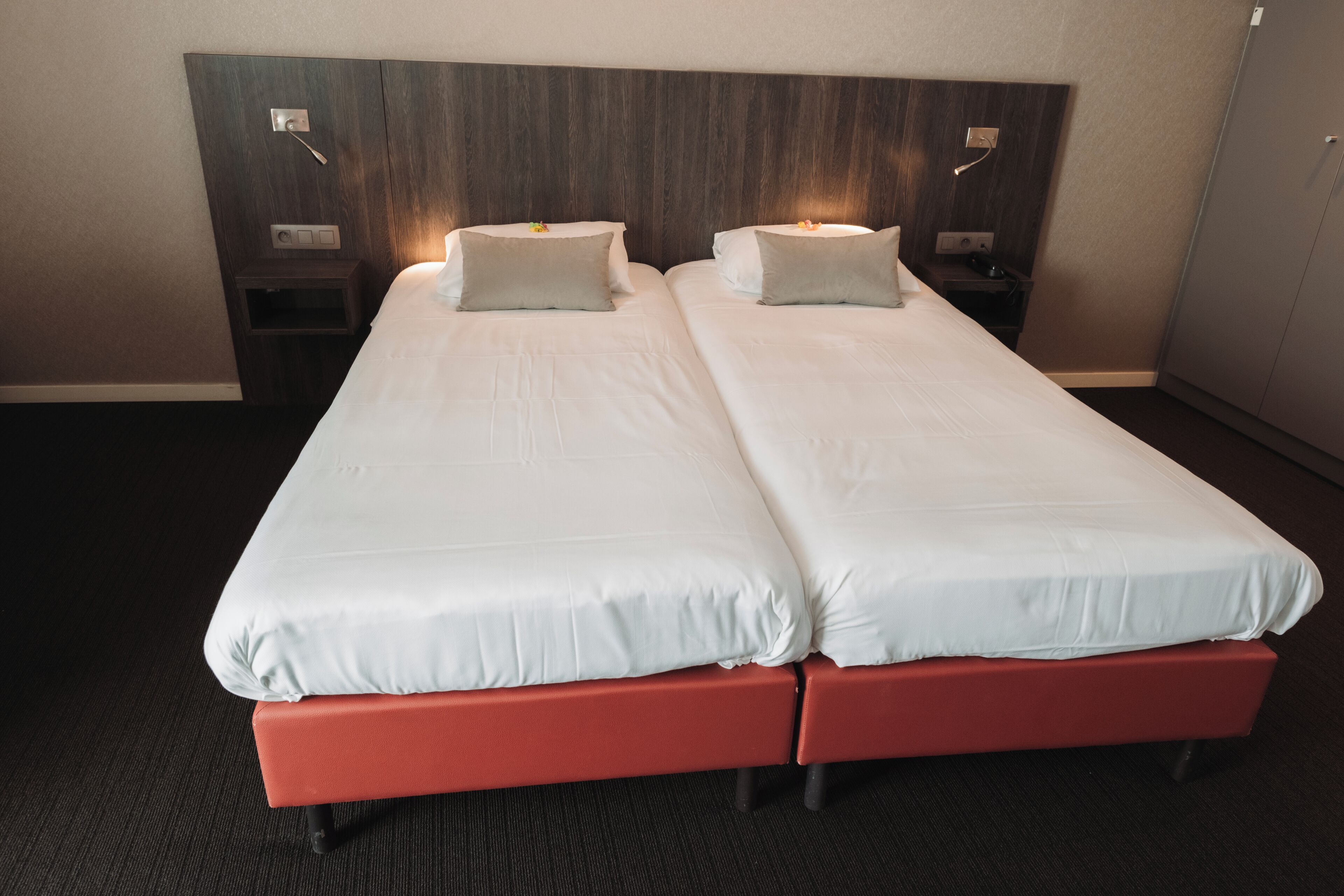 Una cama doble con cabecera de madera, dos mesitas de noche con lámparas y suelo alfombrado.