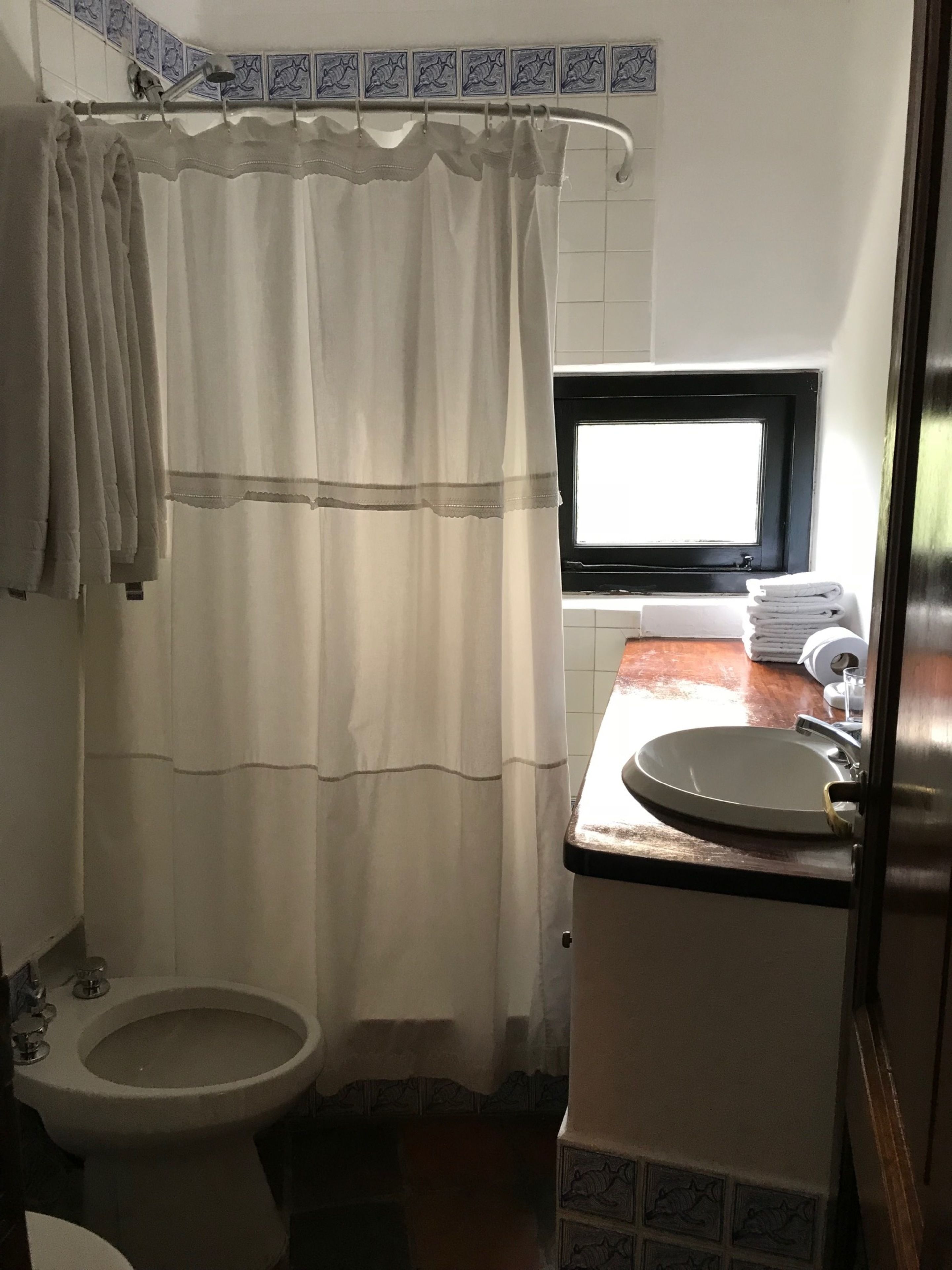 Un baño con inodoro, lavamanos y cortina de ducha.