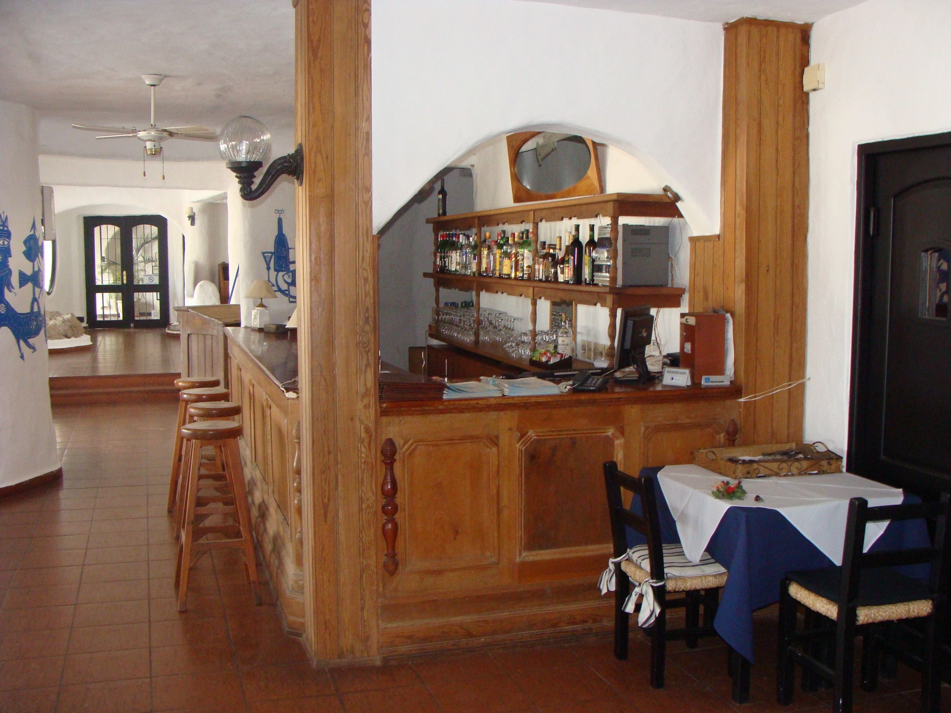 A bar area with wooden furniture, a tiled floor, and a dining table with chairs.