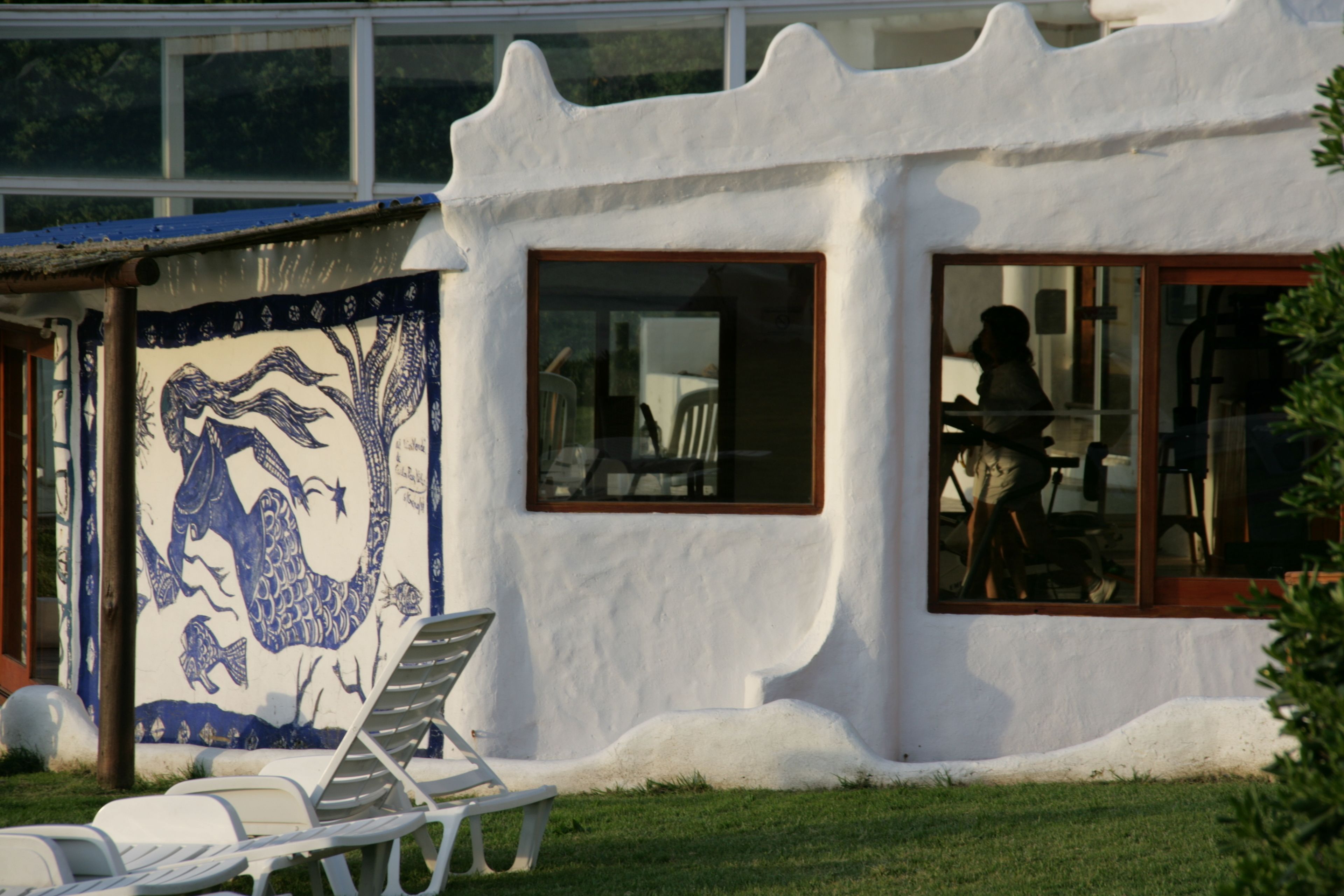 A building with a unique exterior design, featuring a mural and a window with a view of the interior.