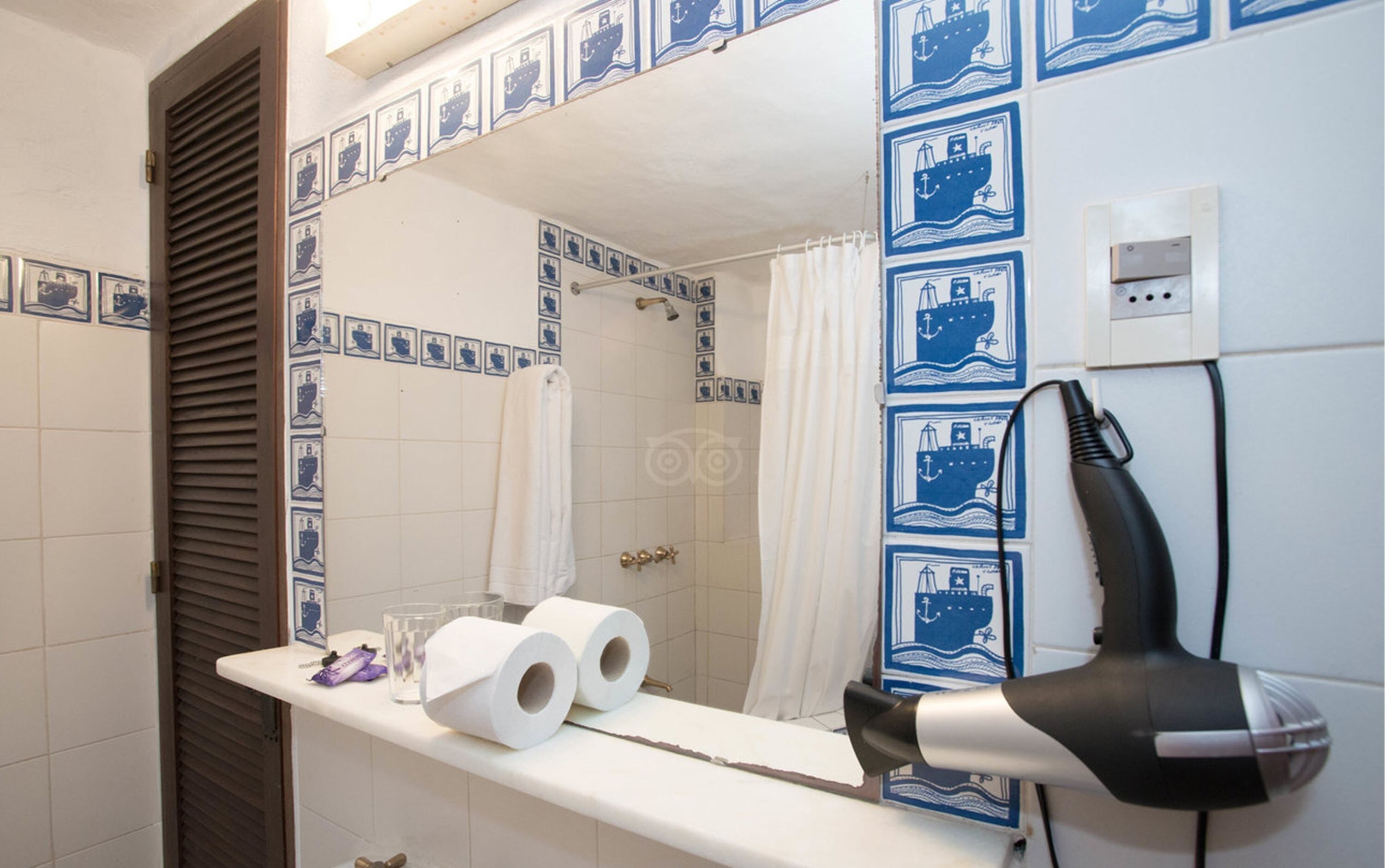 A bathroom with a mirror, a shower curtain, and a hairdryer on the counter.