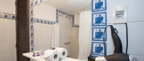A bathroom with a mirror, a shower curtain, and a hairdryer on the counter.