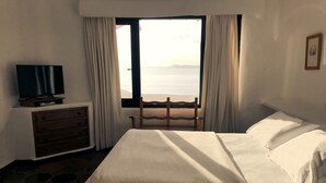 Una camera d'albergo con un letto, una cassettiera, una televisione e una finestra con tende.