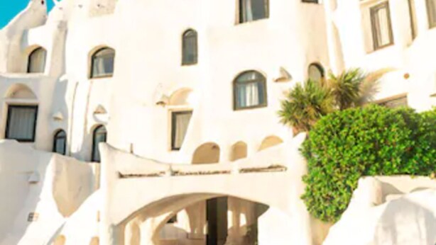 Un edificio bianco con finestre ad arco e una piscina di fronte.