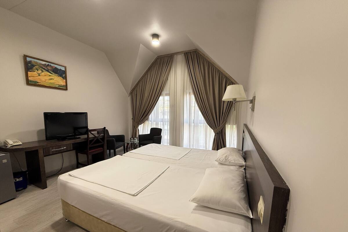 Une chambre d’hôtel avec un grand lit, un bureau avec un ordinateur, une chaise et un tableau au mur.