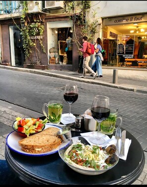 A table with a meal and drinks on a sidewalk. - Casa Suzanna (Tel Aviv)