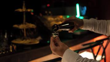 A person pouring a drink into a small glass at a bar.