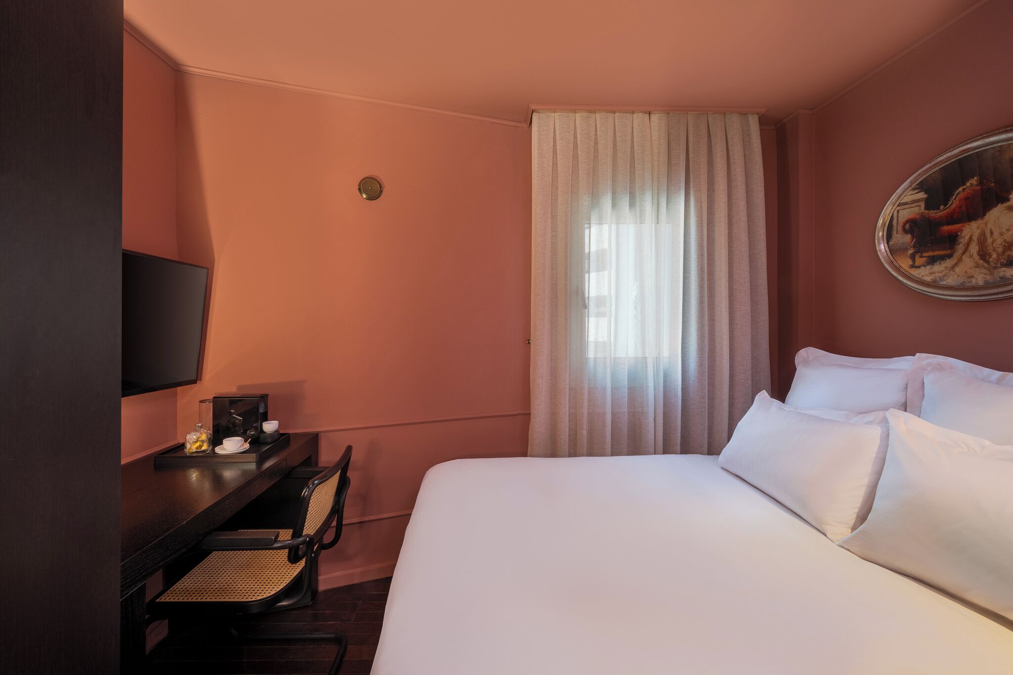 Une chambre d’hôtel avec un lit, un bureau et une chaise, une télévision et un tableau au mur.