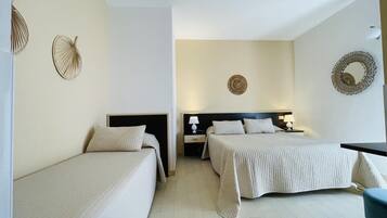 Una habitación de hotel con dos camas individuales, una mesita pequeña y una mesita de noche con lámpara.