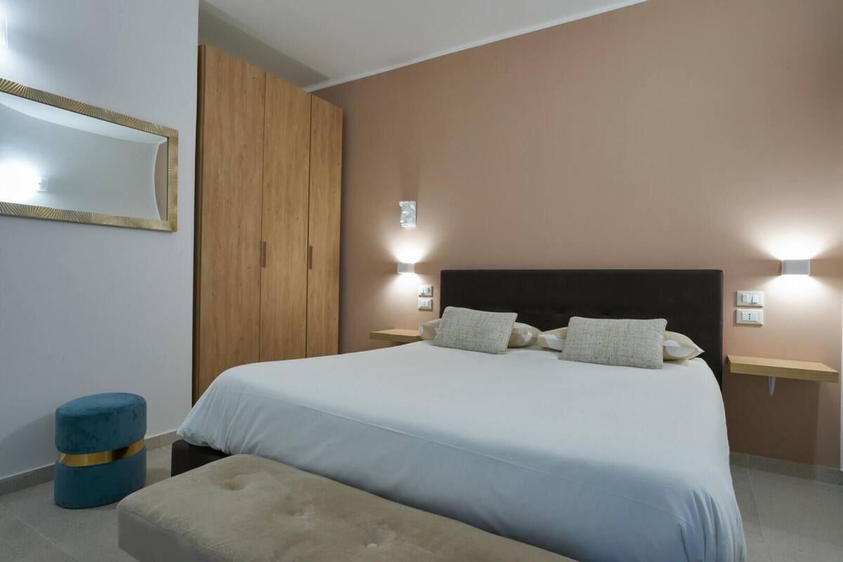 A bedroom with a bed, bedside tables, a wardrobe, and a mirror.