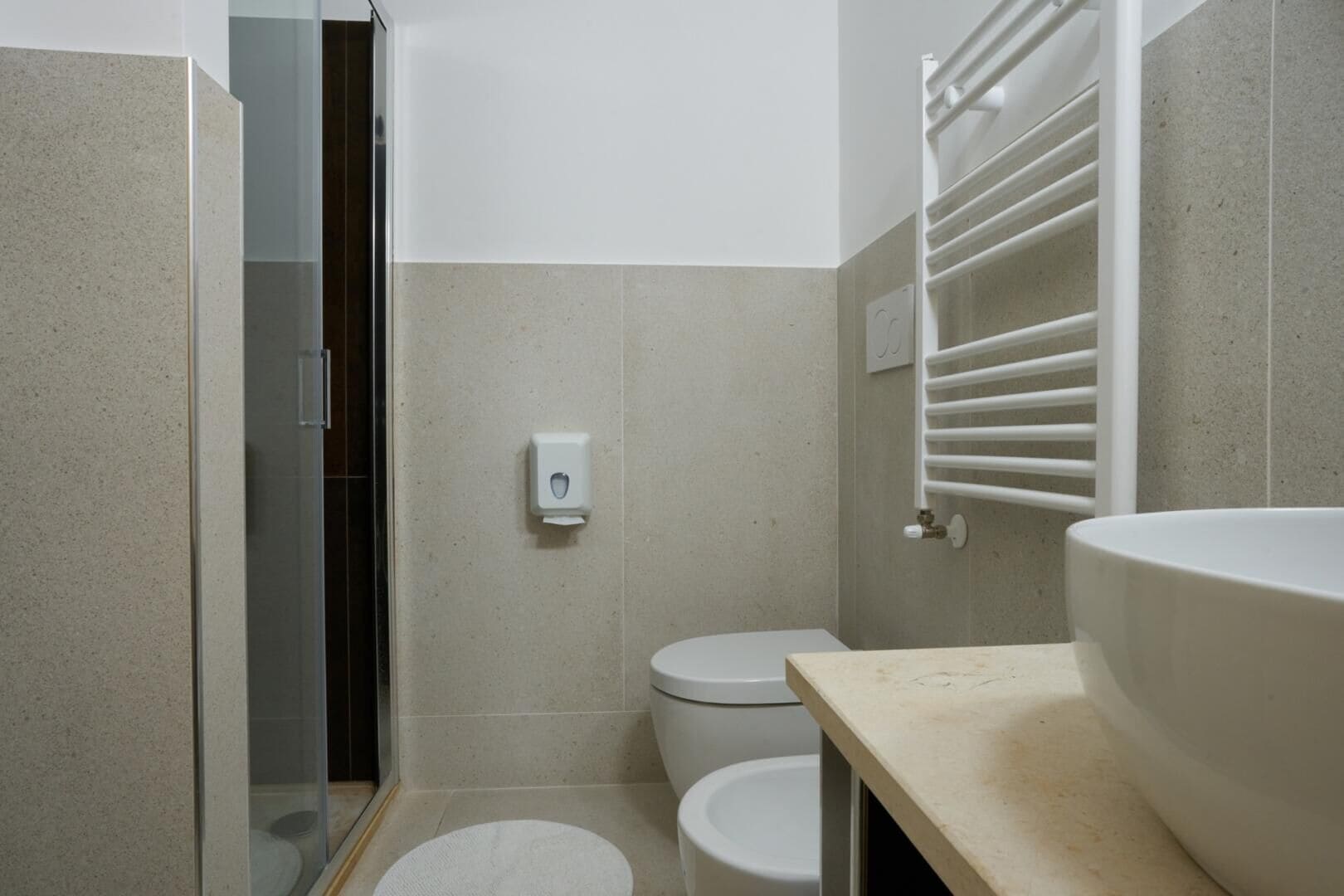 Ein kleines Badezimmer mit Toilette, Waschbecken und einer Duschkabine aus Glas.