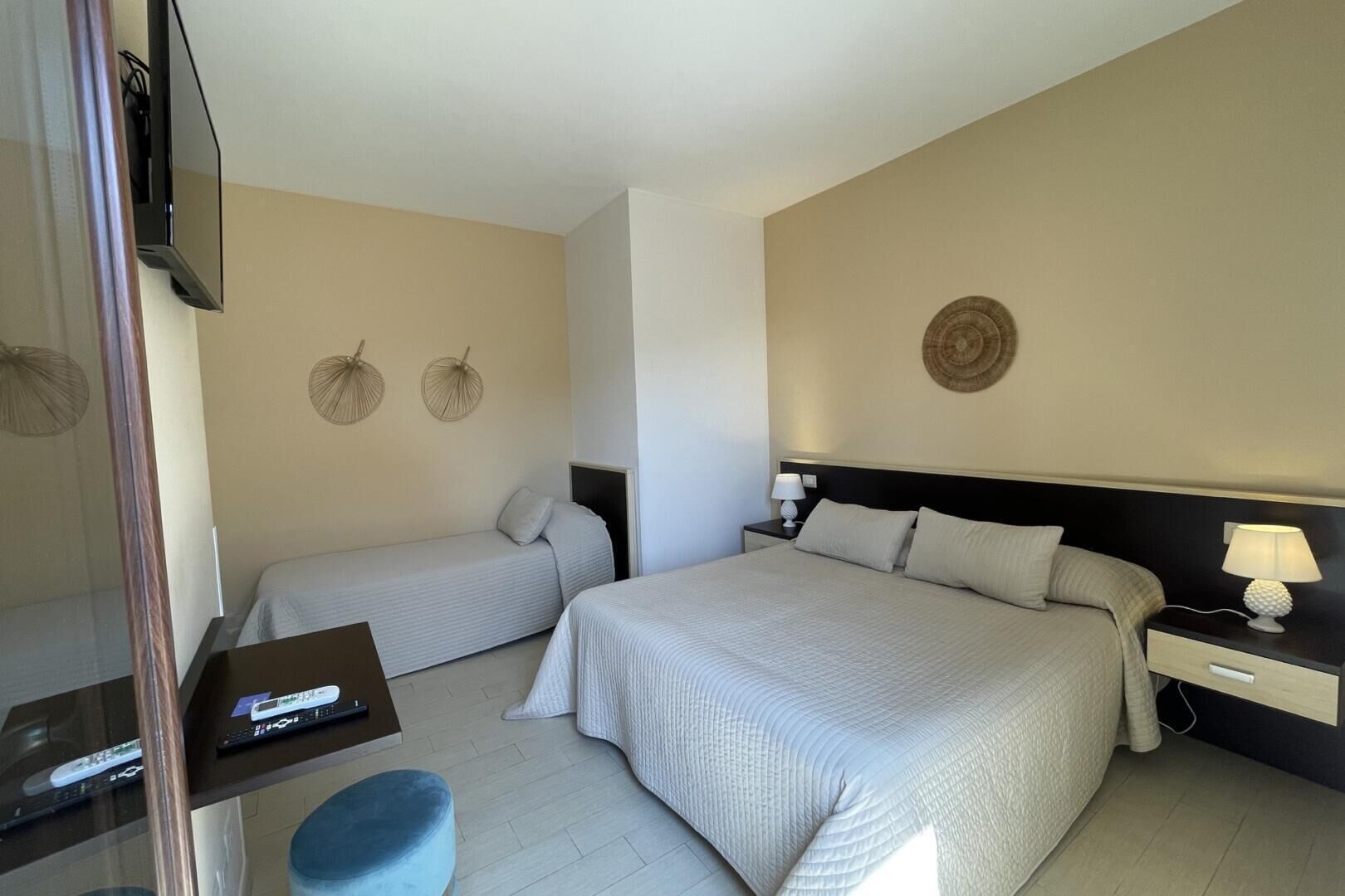 Une chambre d’hôtel avec deux lits, une télévision, un bureau et un petit tabouret.