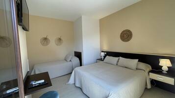 Une chambre d’hôtel avec deux lits, une télévision, un bureau et un petit tabouret.