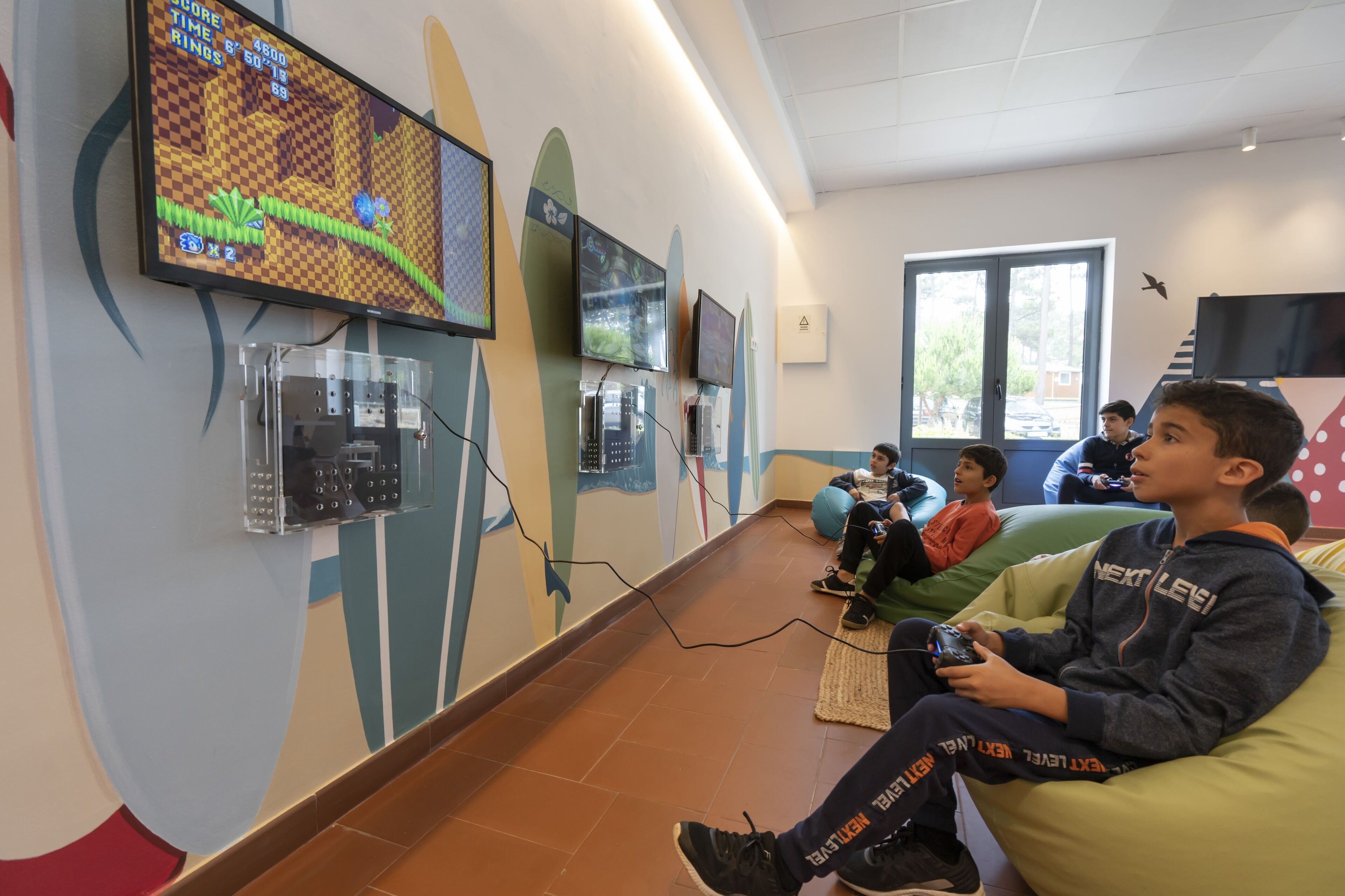 Habitació amb una pantalla gran que mostra un videojoc, un sofà i un nen jugant a videojoc.