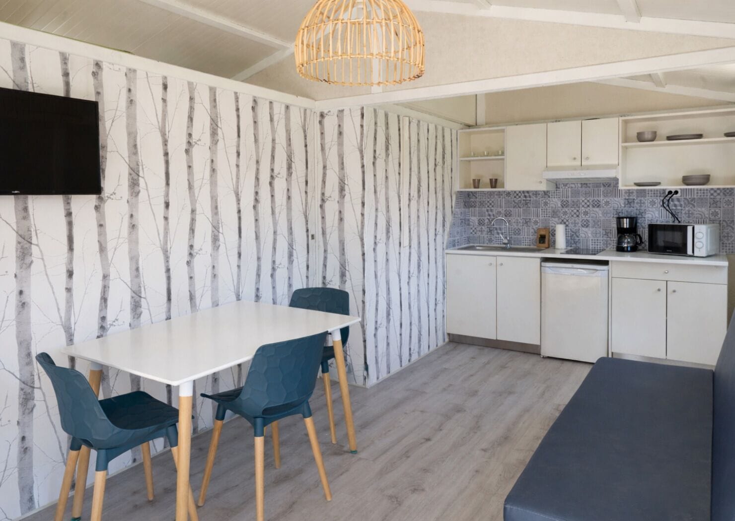 A modern kitchen with white cabinets, a dining table with chairs, a built-in microwave, and a hanging light fixture.