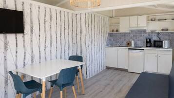 A modern kitchen with white cabinets, a dining table with chairs, a built-in microwave, and a hanging light fixture.