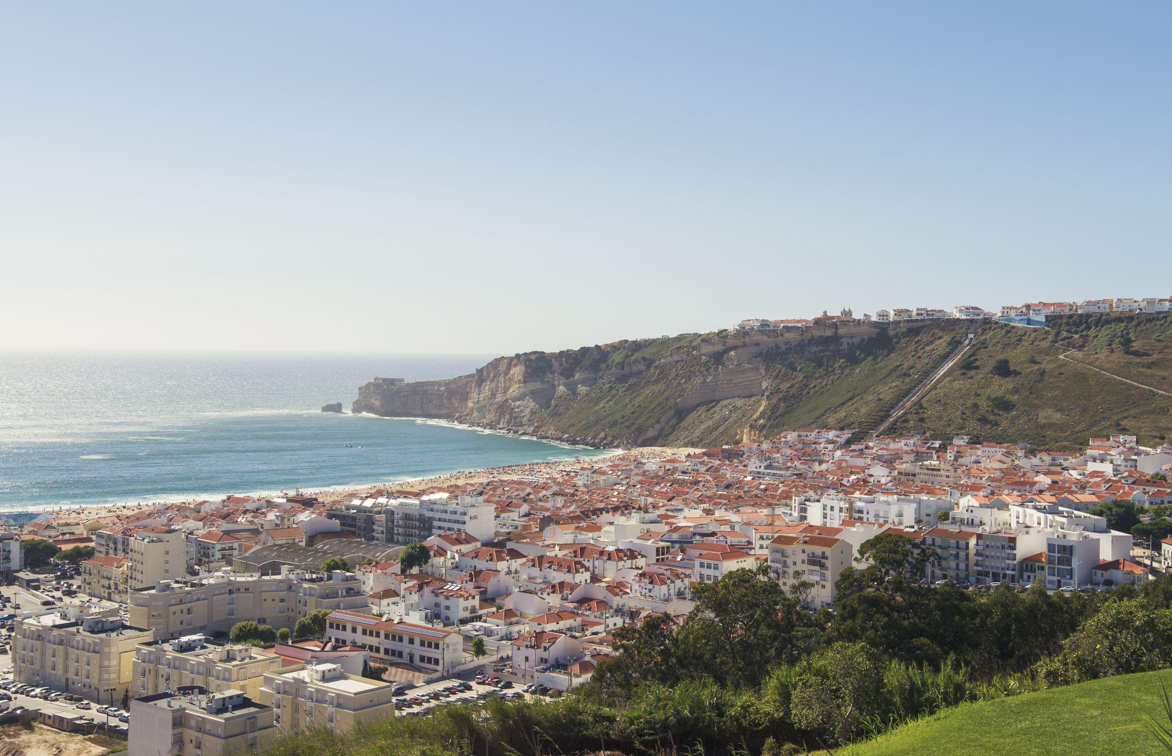 A coastal town with buildings along the beach and a cliff in the background.