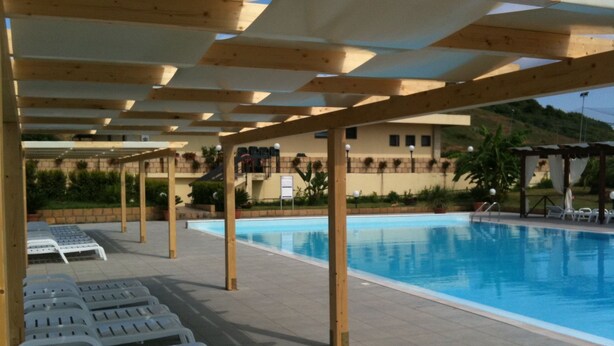 A pool area with lounge chairs and wooden pergolas. - Baia dei Canonici (Borgia)