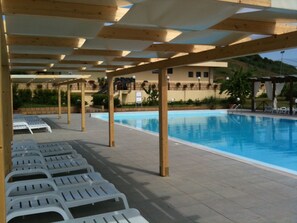 Zona de piscina amb gandules i pèrgoles de fusta.