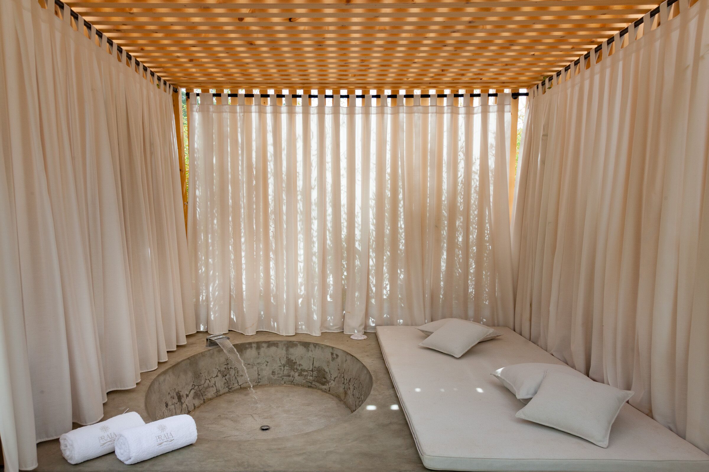 Una stanza spa con una panca a forma di curva, un lavandino piccolo e un soffitto in legno.