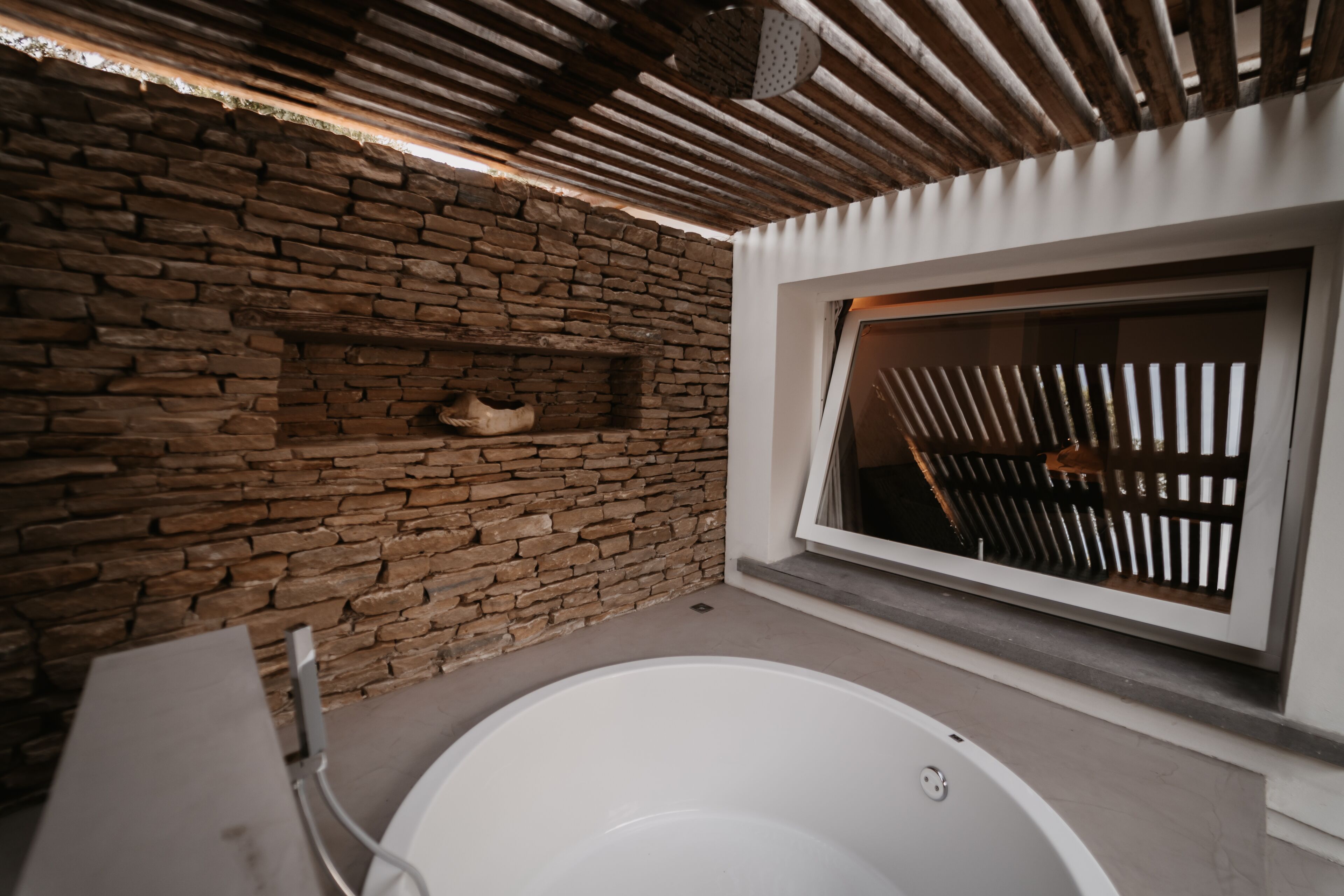 A stone wall, a window with a view, and a bathtub.