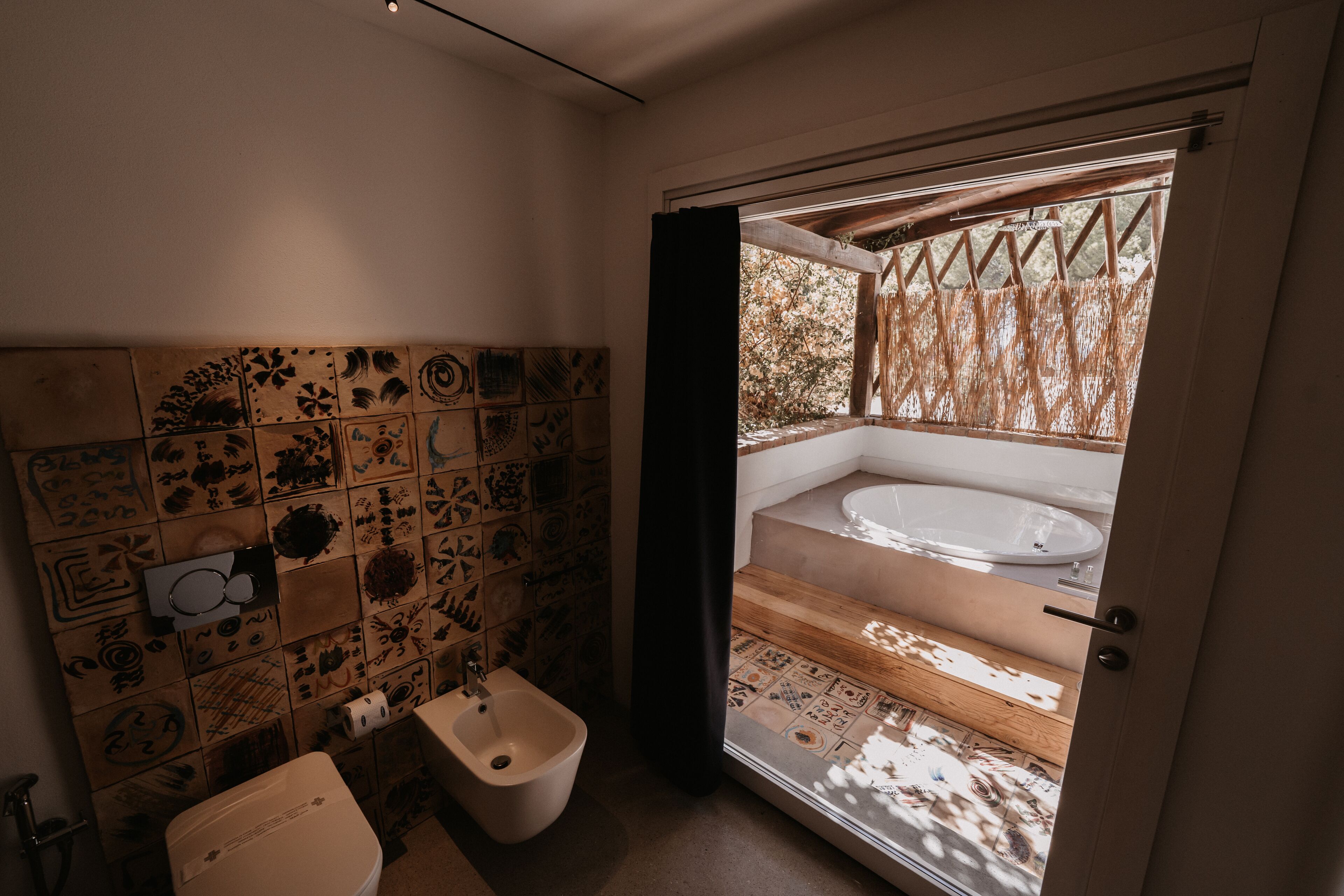 A bathroom with a toilet, bidet, and a bathtub visible through an open door.