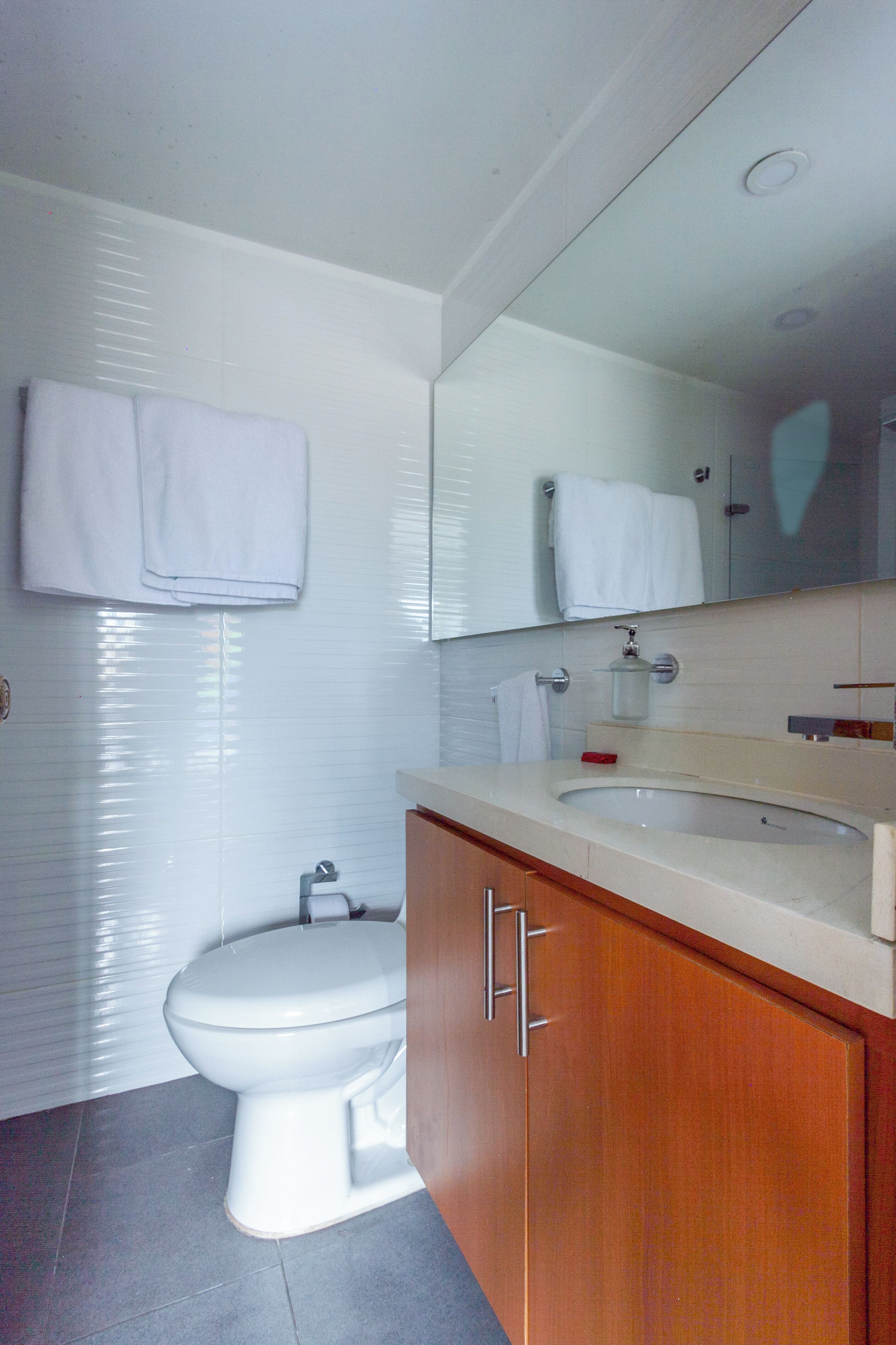 A modern bathroom with a toilet, sink, and mirror.