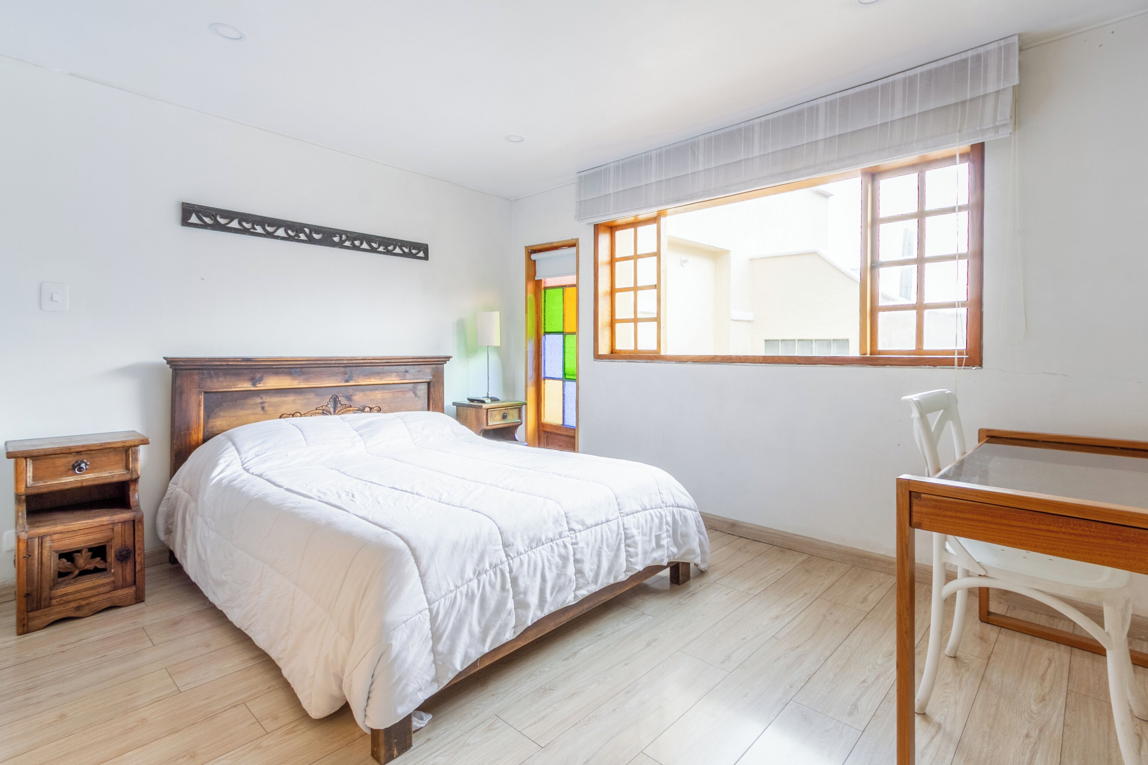Ein Schlafzimmer mit einem Holzbett, einem Schreibtisch und einem Stuhl.