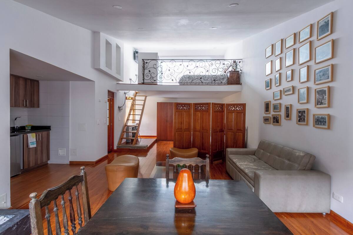 Un vaste espace de vie comprenant une table à manger, un canapé et un escalier menant à une mezzanine.