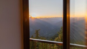 Vista desde una ventana con un paisaje montañoso al atardecer.