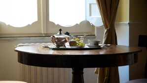 Uma mesa de madeira redonda com um bule, chávenas e uma travessa de fruta.