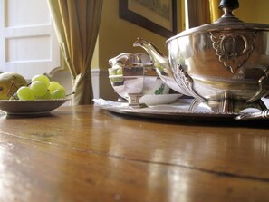 A silver tea set on a wooden table with a bowl of green grapes and a teapot. - Relais Teatro Argentina (Rome)
