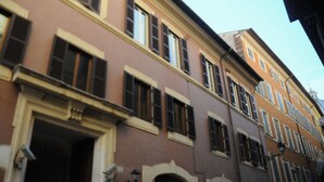 Um edifício de vários andares com características arquitetônicas clássicas, incluindo arcadas e janelas simétricas.