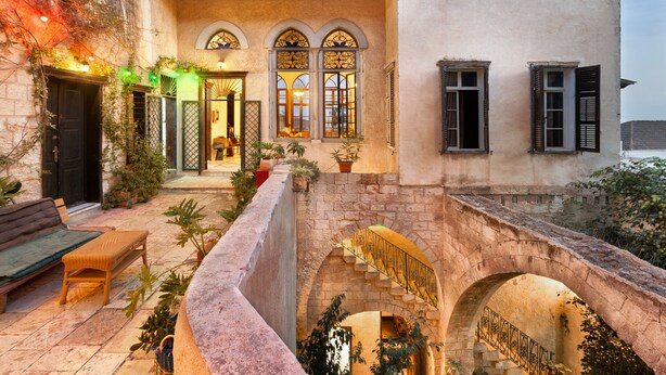A courtyard with a stone bridge, a bench, and potted plants. - Fauzi Azar by Abraham (Nazareth)