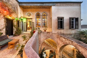A courtyard with a stone bridge, a bench, and potted plants. - Fauzi Azar by Abraham (Nazareth)