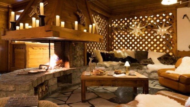 A cozy room with a stone fireplace, wooden ceiling, and a lattice wall with star decorations.