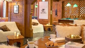 A cozy room with wooden walls, a sofa, a small table with a cup and pastries, and a book titled "The Dog in Photography".