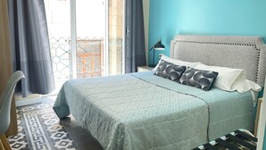 A bedroom with a bed, a nightstand, a lamp, and a view of the outside. - Alicante San Nicolás (Alicante)
