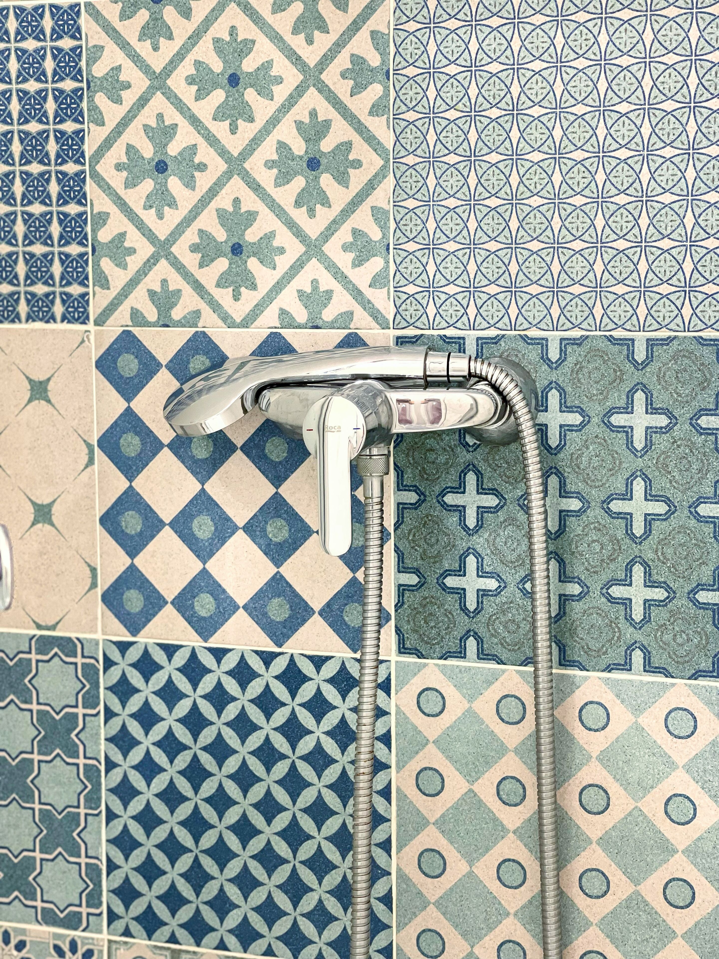 A bathroom with a shower and a sink, tiled with various geometric patterns.