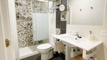 A bathroom with a shower, toilet, sink, and a mirror.