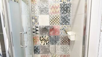 Une douche dotée d’une porte en verre et d’un mur carrelé orné de différents motifs géométriques.