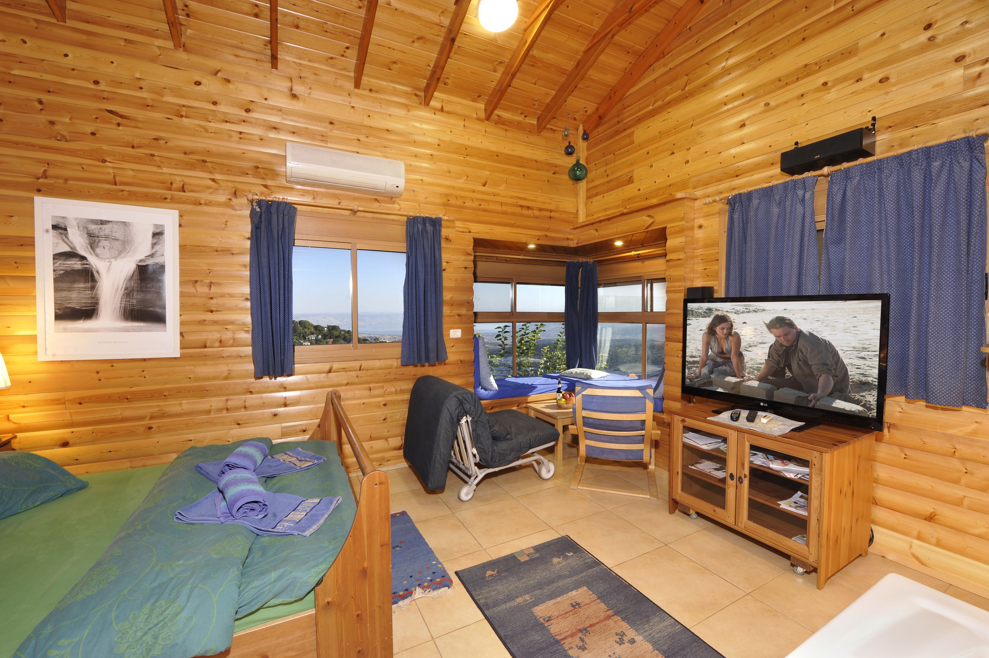 Una cabaña de madera con cama, escritorio, televisor y vistas al exterior.