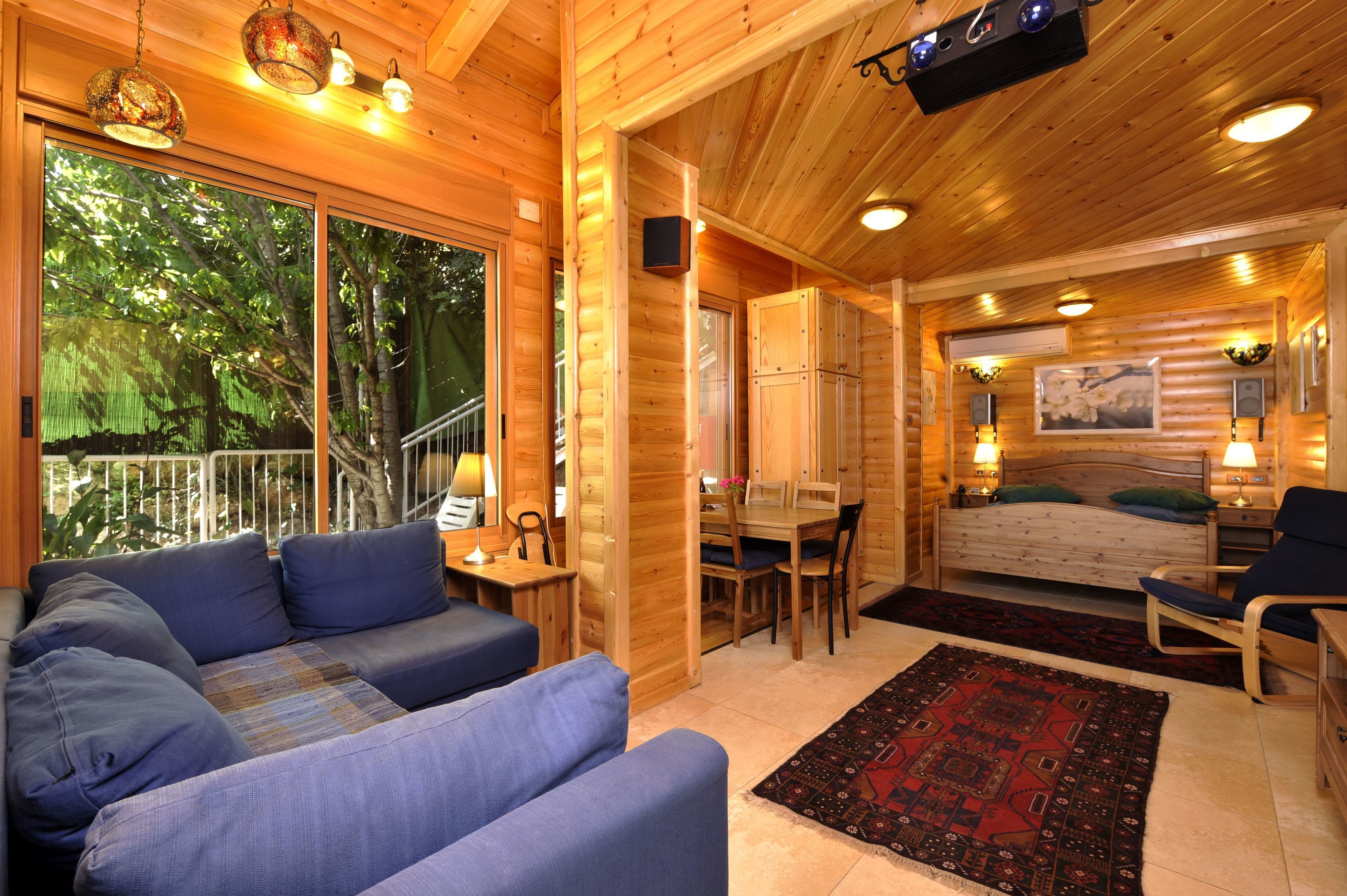 A cozy log cabin interior with a sofa, dining table, and a bed.