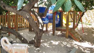 A playground with a slide, climbing structures, and a tree.
