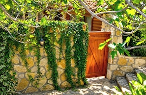 A stone wall with a wooden gate, surrounded by greenery. - Ohn-Bar Guesthouse (Merom HaGalil)